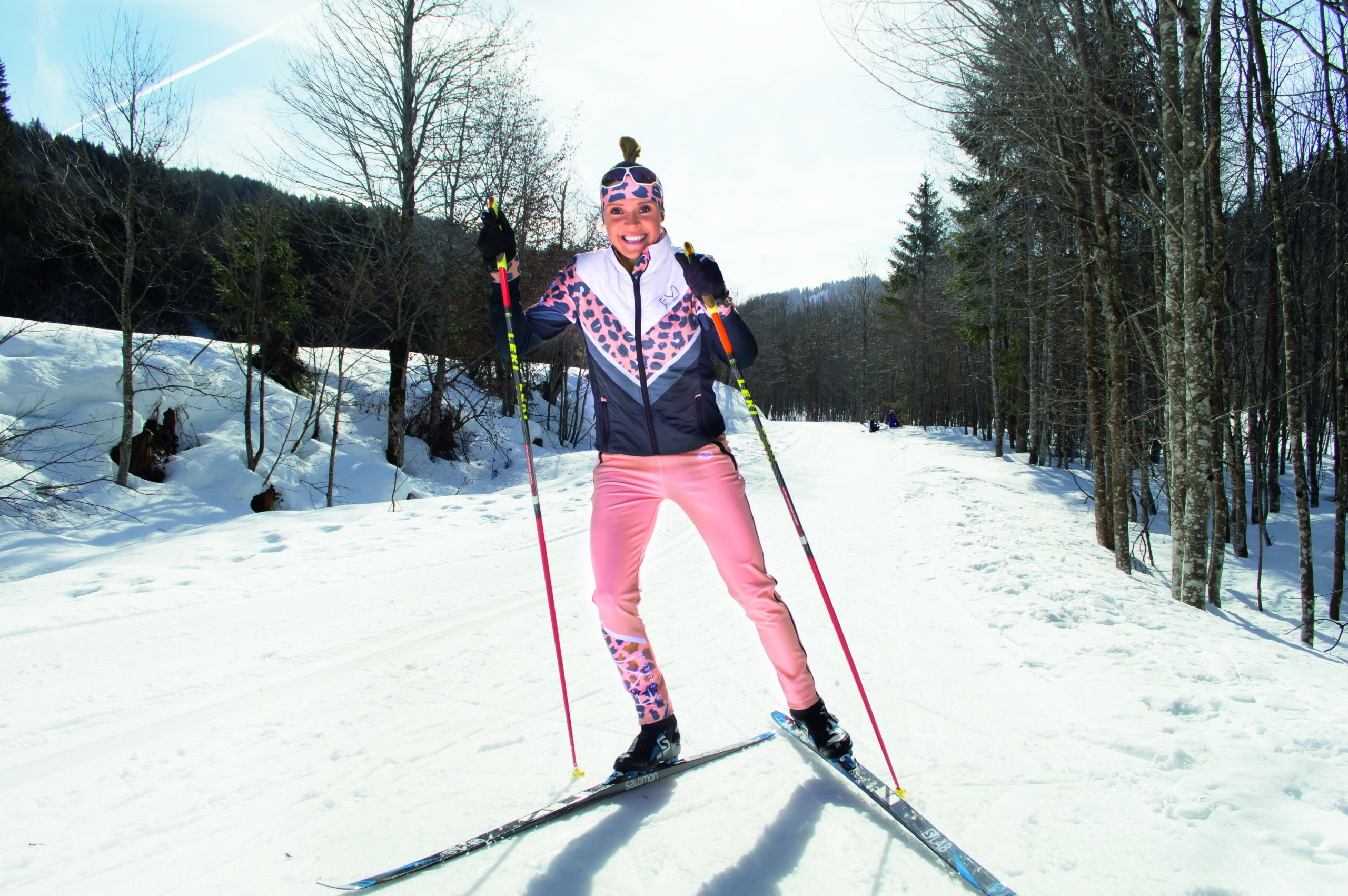 Evi Sachenbacher-Stehle in rosa Hose und grau-weiß-rosa Jacke inkl Stirnband beim Langlauf.