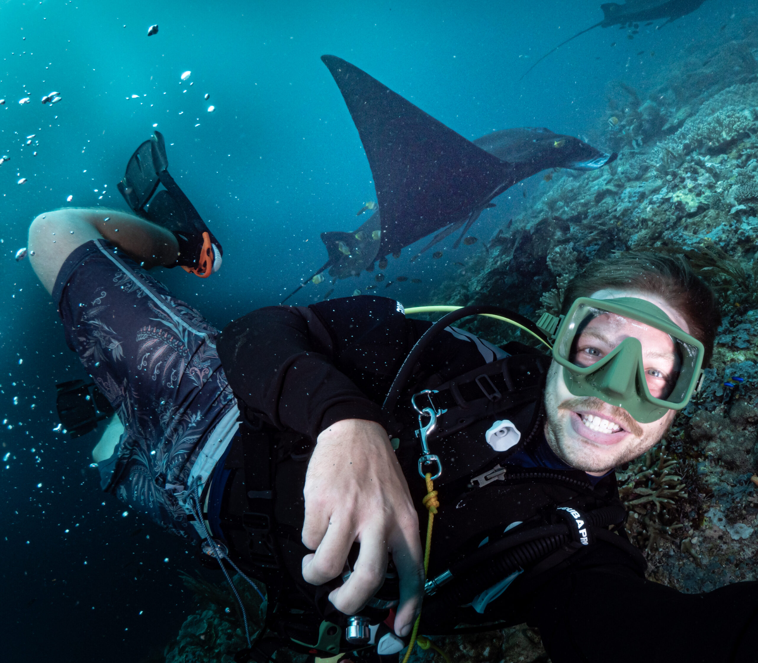 Keynote Speaker und Umweltaktivist Tim Noack schaut bei einem Tauchgang mit einem Mantarochen im Hintergrund in die Kamera.